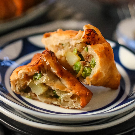 low angle shot of a potato samosa cut in half to reveal the filling.