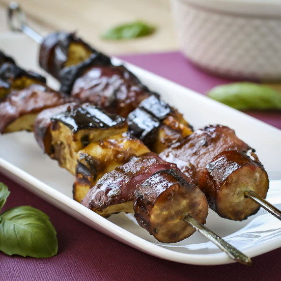Close up angled shot of two halloumi kekbabs on a white rectangle plate on a maroom table cloth.