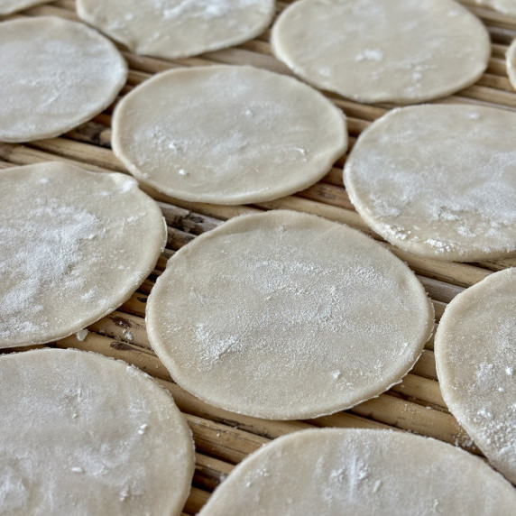 Gyoza wrappers on a bamboo table.