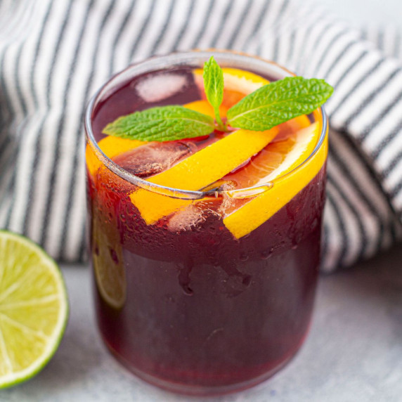 Kombucha mocktail in glass with mint and oranges in it.