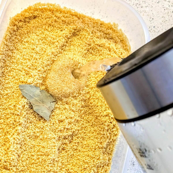 An electric kettle pouring boiling hot water into a container with couscous