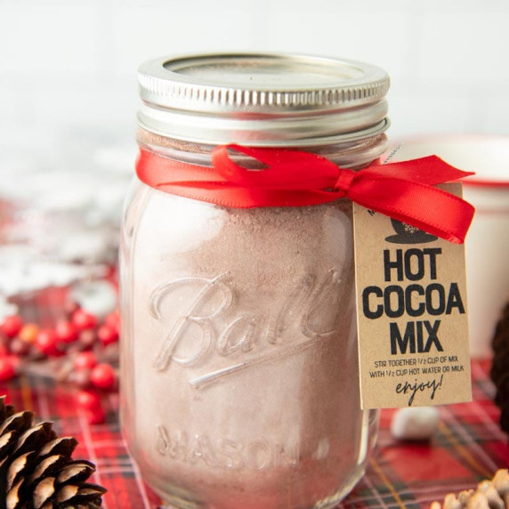Pint jar of homemade hot cocoa mix packaged up for gifting with red ribbon and gift tag.