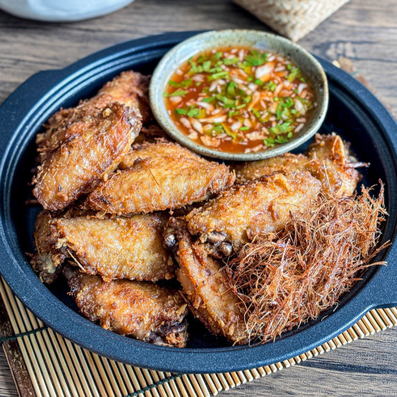 Lemongrass fried chicken wings with dipping sauce in a black serving dish.