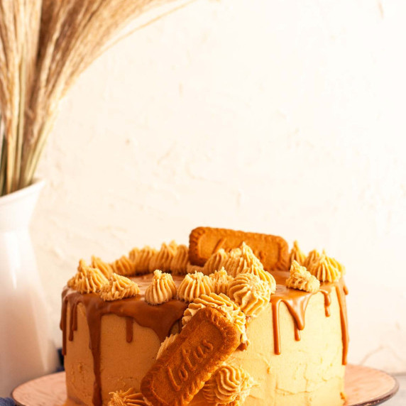 A Lotus Biscoff drip cake with biscoff buttercream frosting and cookies on a plate.