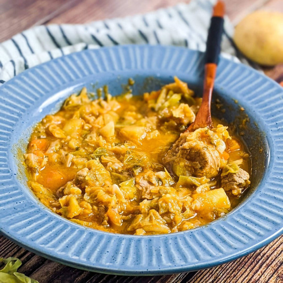 Cabbage and pork stew served in a blue bowl.
