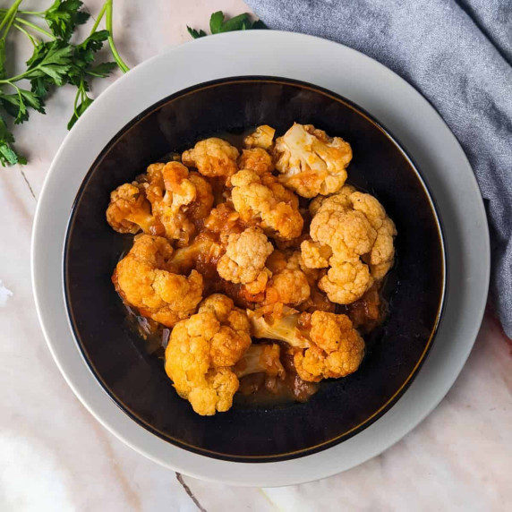 Braised cauliflower served in black bowl.