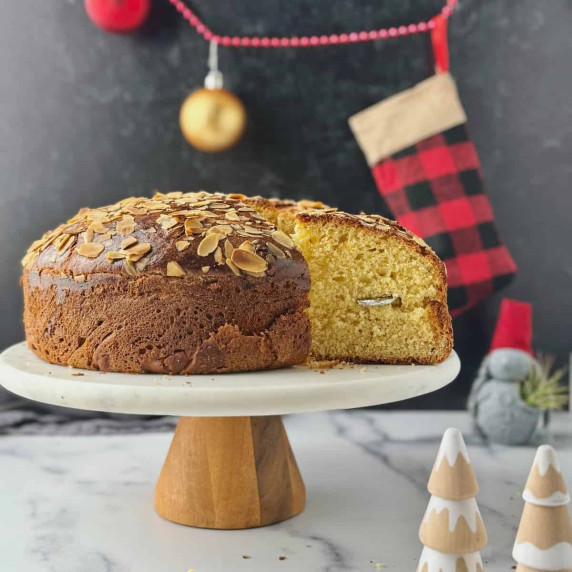 Vasilopita tsoureki on a stand with a cut piece out and the lucky coin in.