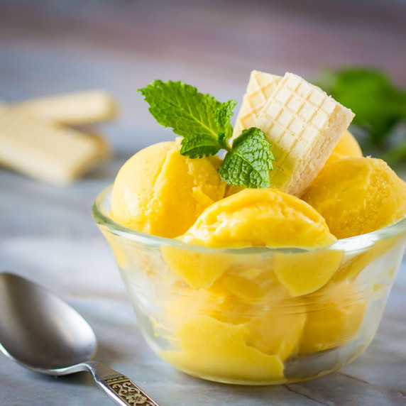 Side close up shot of frozen yogurt in a small clear bowl garnished with mint leaves and shortbread.
