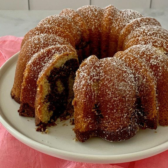 Marble Bundt Cake on a white cake stand with slice removed.