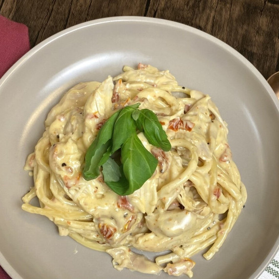 A dish filled with marry me chicken pasta topped with fresh basil leaves.
