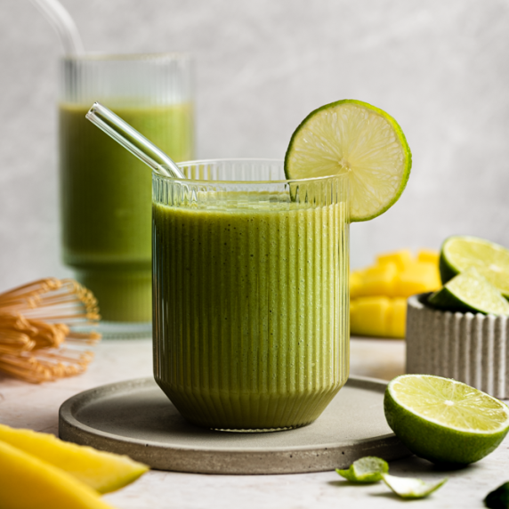 Mango matcha smoothie arranged in an aesthetic cups with mangoes and matcha on the side