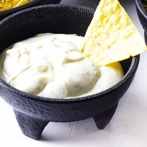 mexican white sauce, salsa, and guacamole in black bowls.