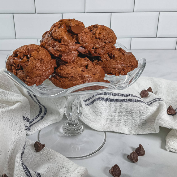 Mocha Chocolate Truffle Cookies stacked on a glass cake stand surrounded by a white towel.