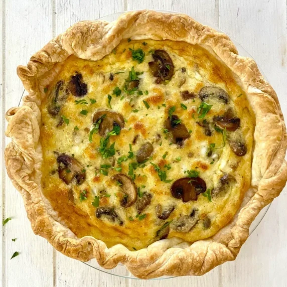 mushroom quiche with a golden brown puff pastry crust on a white board
