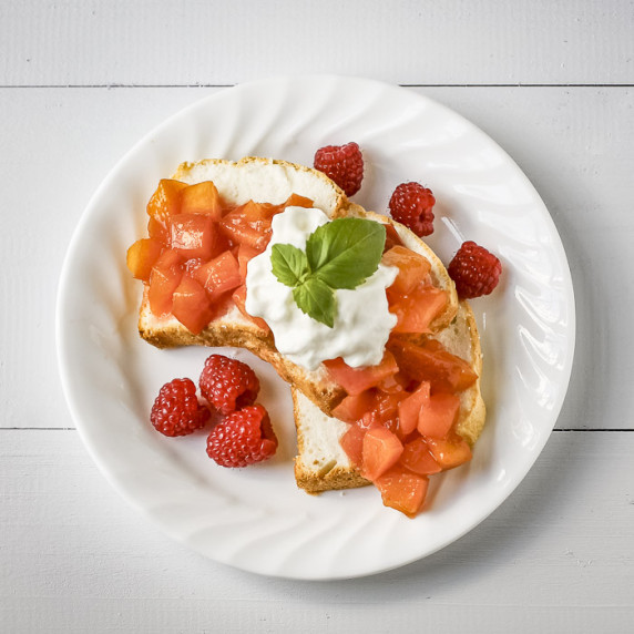 Overhead shot of nectarine compote on slices of cake garnished with ice cream and mint