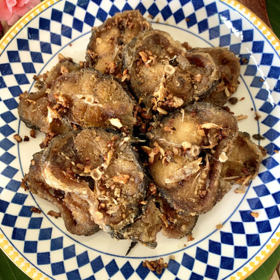 Top-view of pan fried catfish topped with crispy garlic.