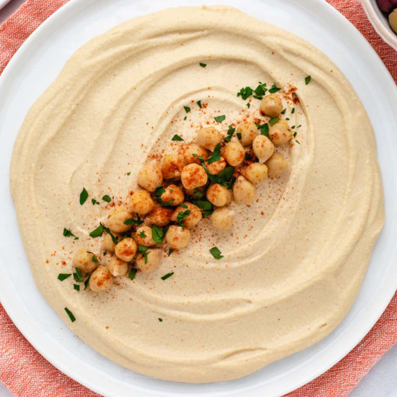 Oil-free hummus on a plate with chickpeas and chopped parsley.