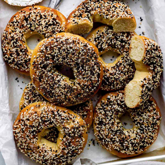 Onion bagels on a baking sheet layed with parchment paper.