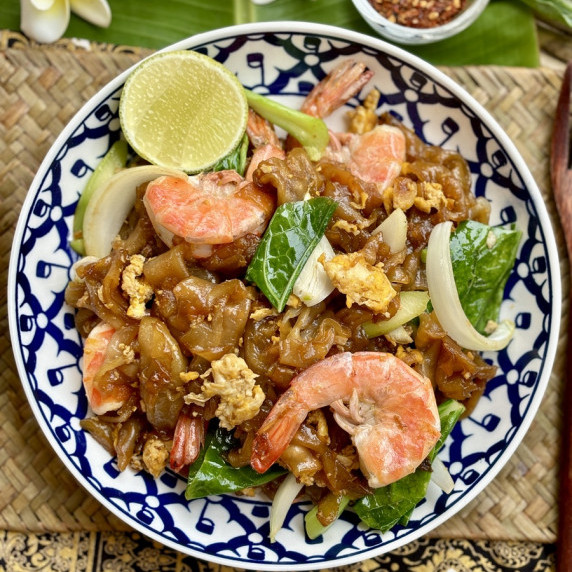 Pad see ew shrimp served in a patterned dish.