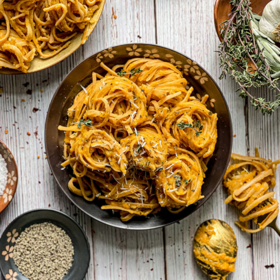 Pasta with Roasted Garlic Butternut Squash Sauce on a gray plate and a white wooden surface.