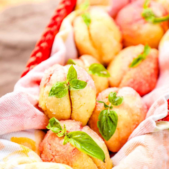 a basket of italian peach sandwich cookies with peach buttercream garnished with basil.