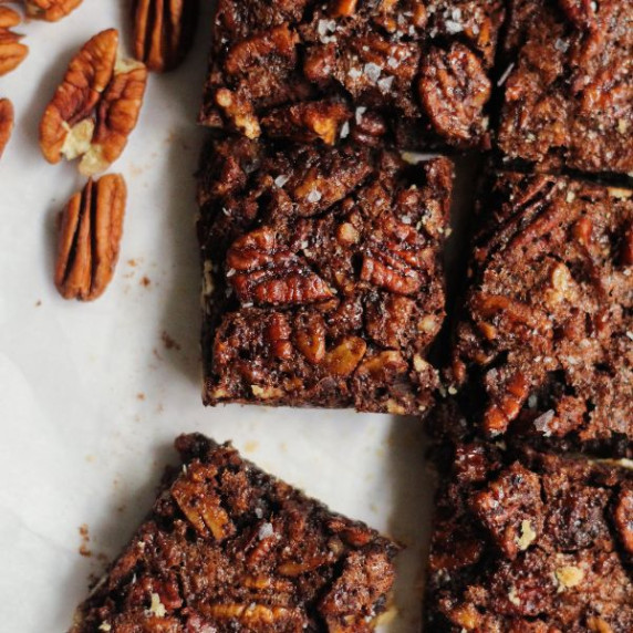 Pecan shortbread bars with flaky salt stacked on a white plate.