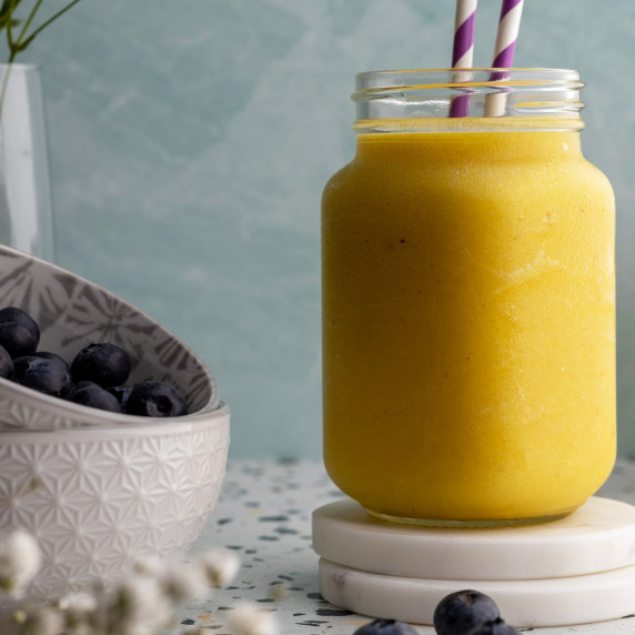 Pineapple mango smoothie in a jar on a coaster