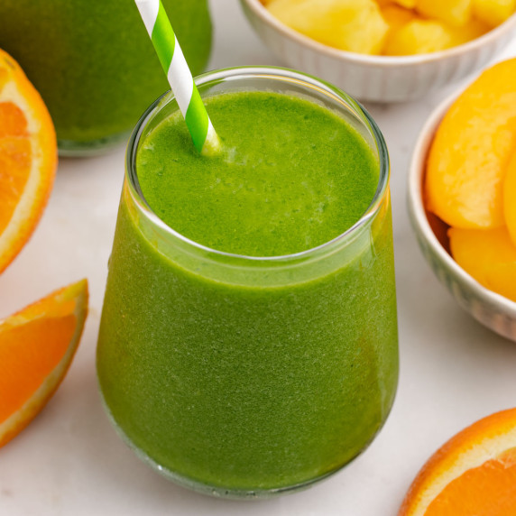 Pineapple peach smoothie in a glass with a straw.