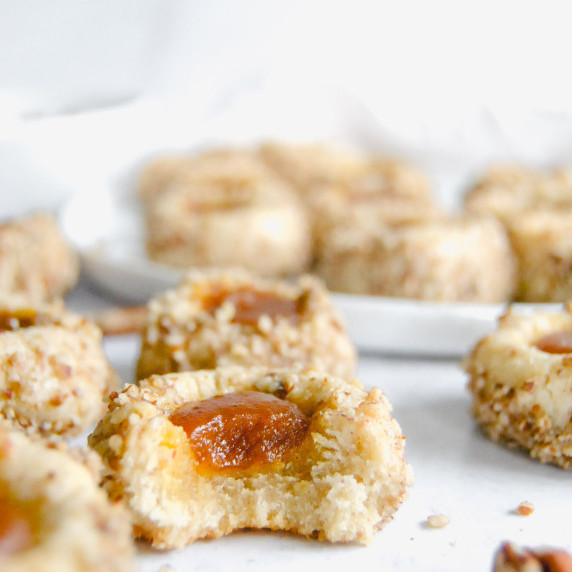 pumpkin butter pecan thumbprint cookie with bite taken out on marble background