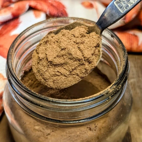 A jar of pumpkin pie spice with a spoonful over the top. 
