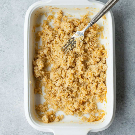 Fluffy quinoa in a baking dish with a fork resting on top of the grains.