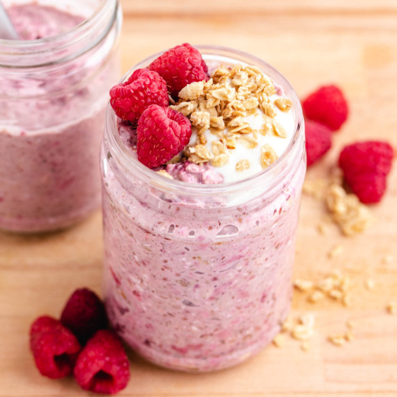 Raspberry overnight oats in a jar with raspberries and granola on top.