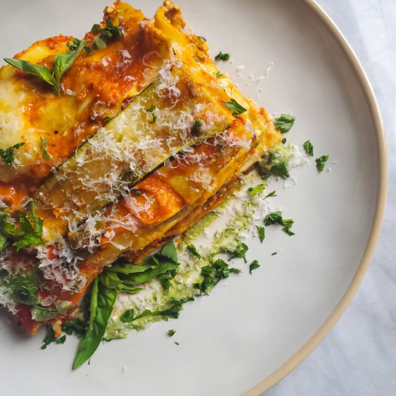 Lasagna on a gold trimmed, pearl white plate.