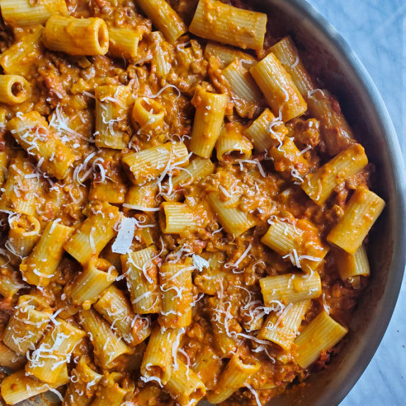 A large skillet full of rigatoni dressed in a lentil Bolognese.