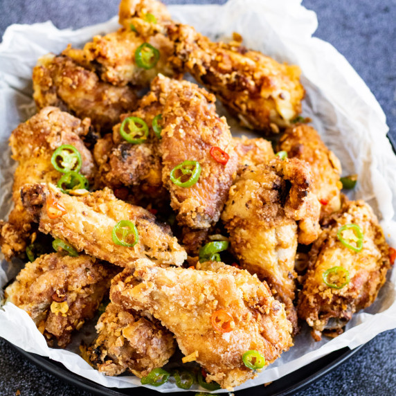 low angle shot of a basket of salt and pepper chicken wings.