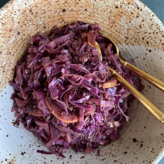 sautéed red cabbage is piled high in a large, rustic pottery-style bowl