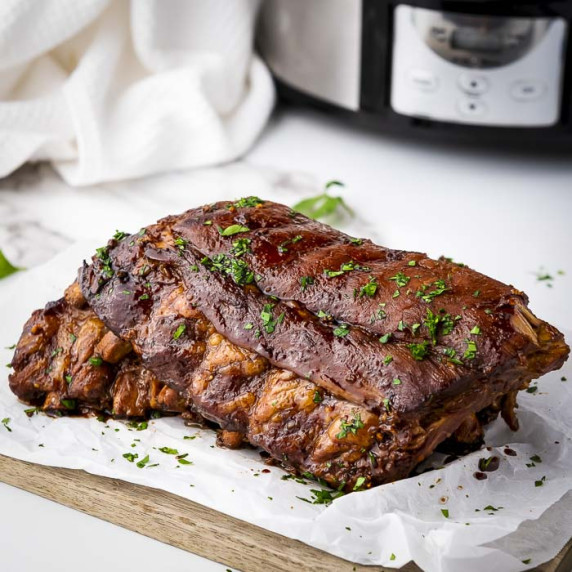 Side close up shot of multiple ribs garnished with parsely on a piece of butcher paper.