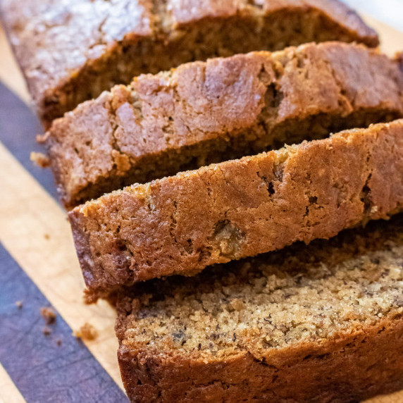 Banana bread sliced on a striped wooden cutting board