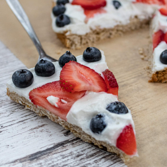 Slice of fruit pizza covered in blueberries and strawberries