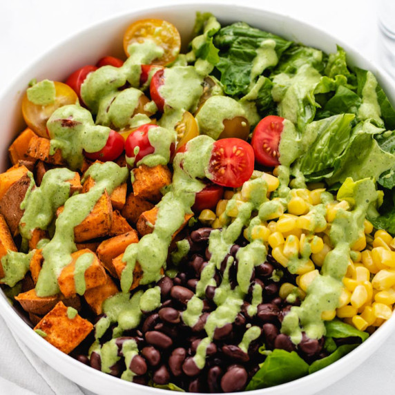 Vegan southwest sweet potato bowl with black beans, corn, tomatoes, and cilantro dressing.
