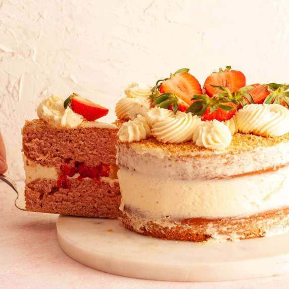 Cutting a slice of strawberry cake with coconut buttercream.