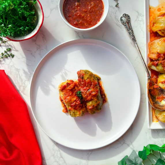 Stuffed cabbage rolls on a white plate with a red napkin on the side.
