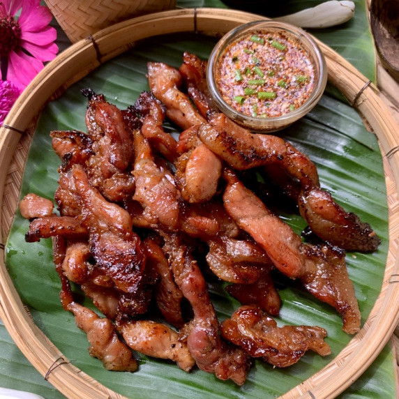 Top-down view of authentic Thai pork jerky and a spicy chili dipping sauce.