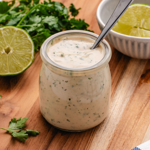 Lime tahini dressing in a glass jar with a spoon.
