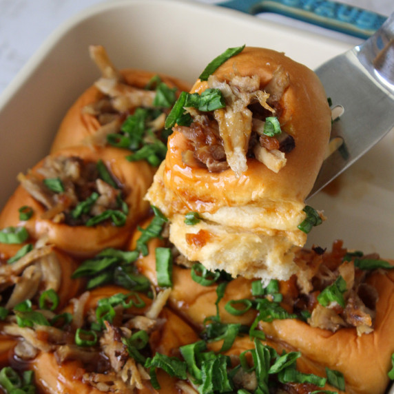 A pulled pork teriyaki slider with scallions on Hawaiian rolls