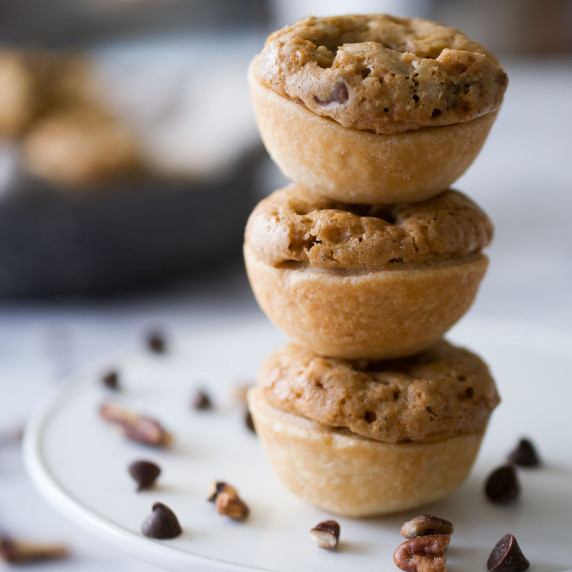 Three mini derby pies stacked in a tower on a white plate.