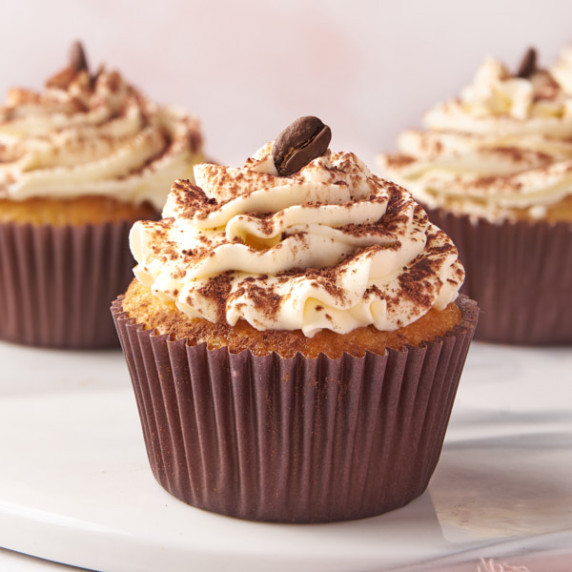 3 tiramisu cupcakes on a marble serving board