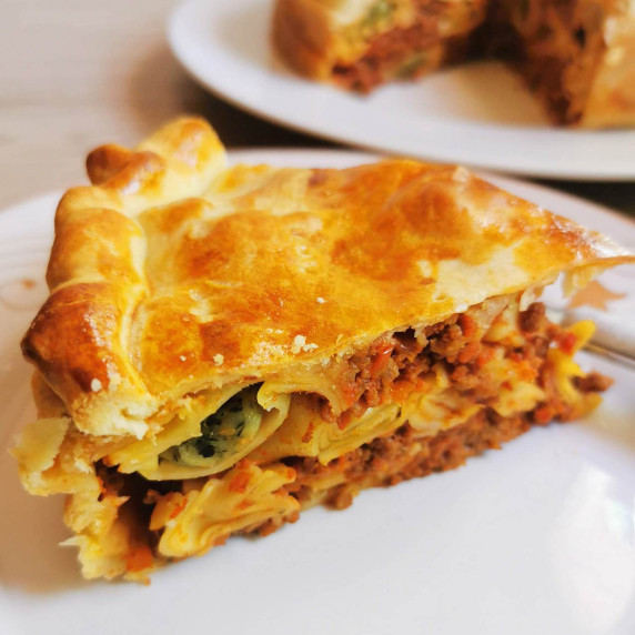 A slice of tortellini bolognese pasta pie on a white plate