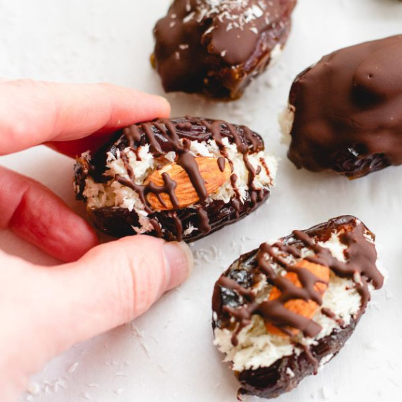 two fingers holding a Healthy Almond Joy Candy Bar on a white paper 