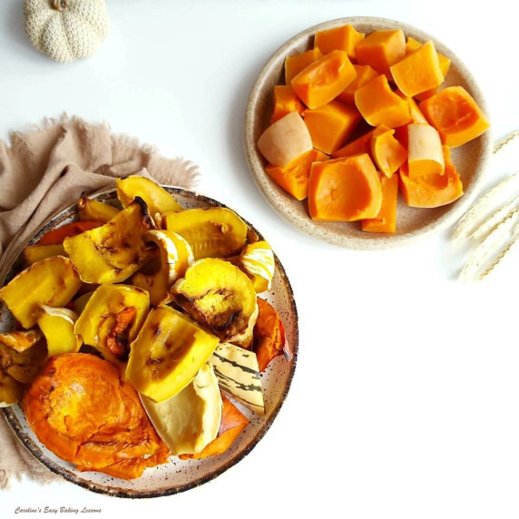 Overhead image of 2 trays of various roasted pumpkins & squash pieces on white background.